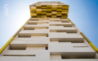 Close-up showing Yellow Kente-patterned facade installed underneath cantilever on completed 27 storey Alto Tower (ahmm.co.uk)